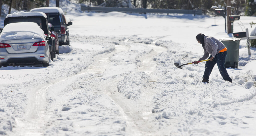 A photo of a person shoveling snow off a road in Greensboro after the December 2018 storm