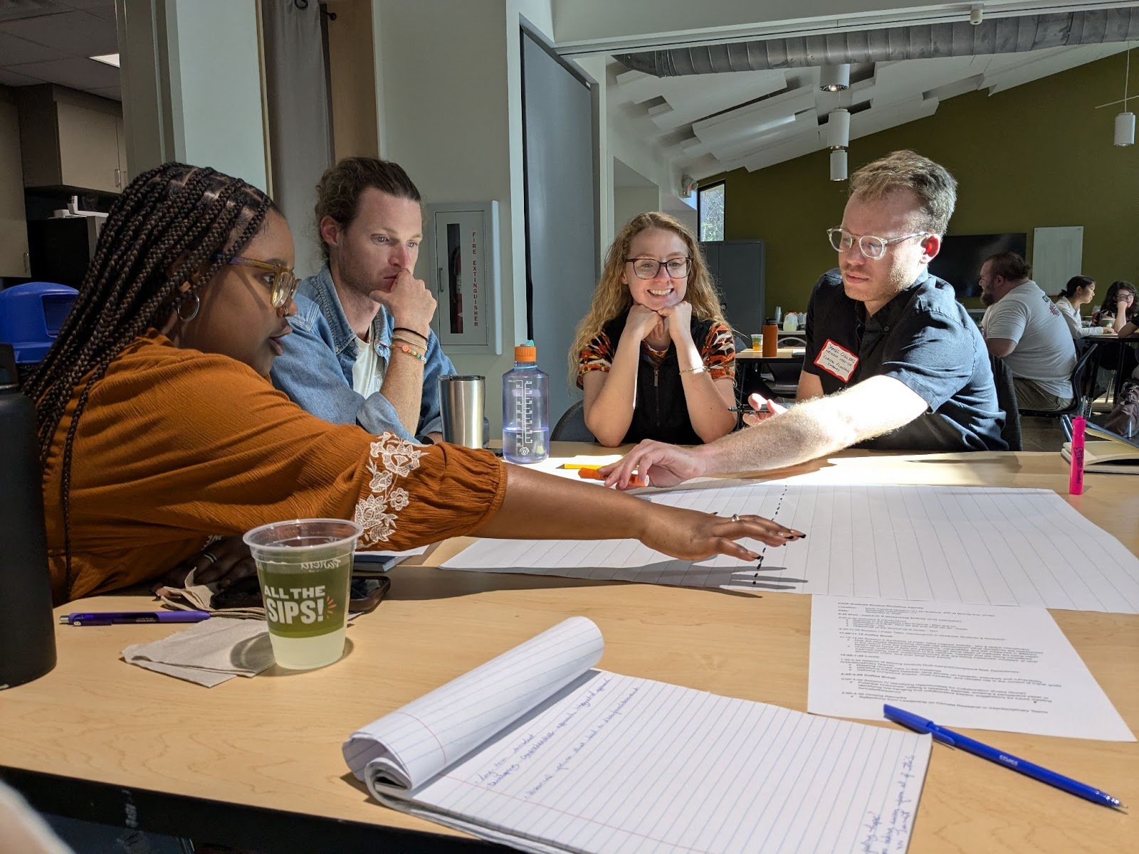 Four students at a table brainstorm how to best map climate risk in the Carolinas. Two students gesture across a large paper