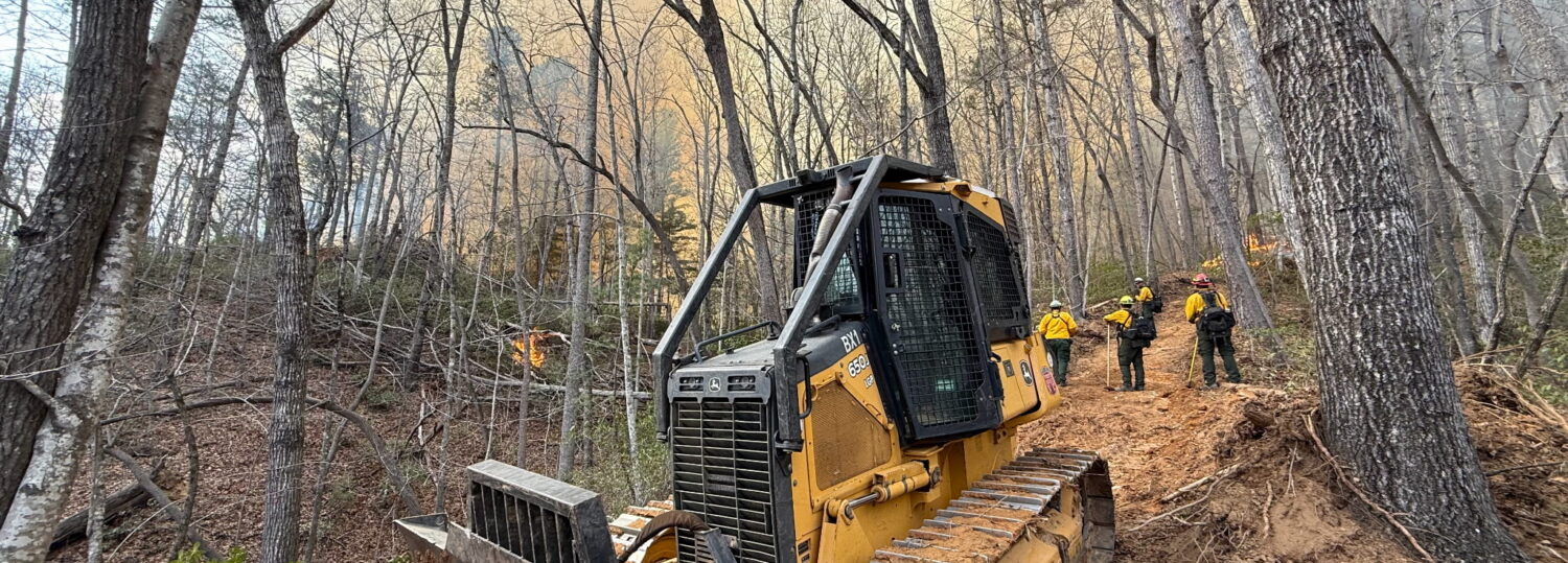 A photo of a dozer working on a containment line at the Deep Woods fire in March