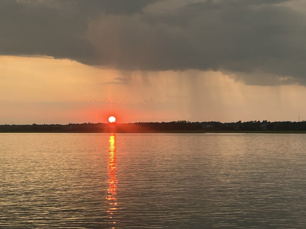 A photo of the sunset at Topsail Island with a rain shower visible in the distance