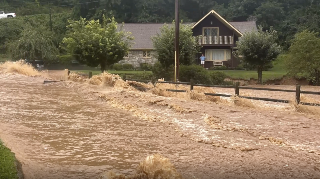 A photo of the Pigeon River rushing past a home during Tropical Storm Fred